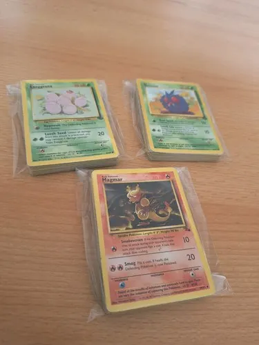 Three bagged bundles of cards on a table, an Exeggcute, a Poliwag and a Magmar on top.