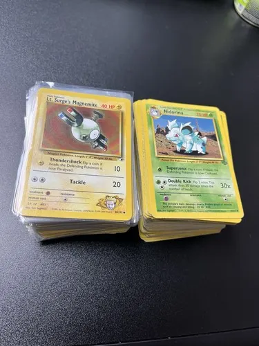 Two thick stacks of unsorted cards side by side, a Lt. Surge's Magnemite and a Nidorina on top.